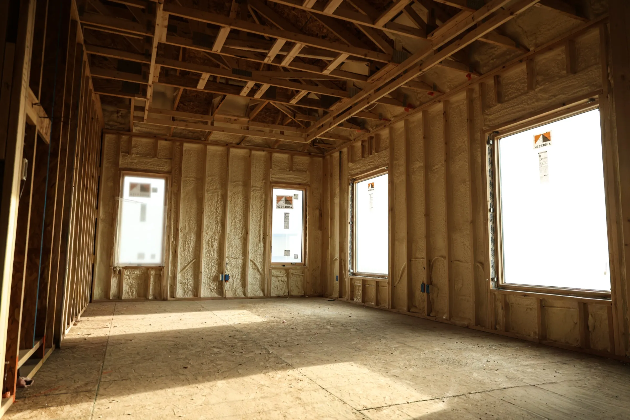 Installer applying spray foam in a framed space